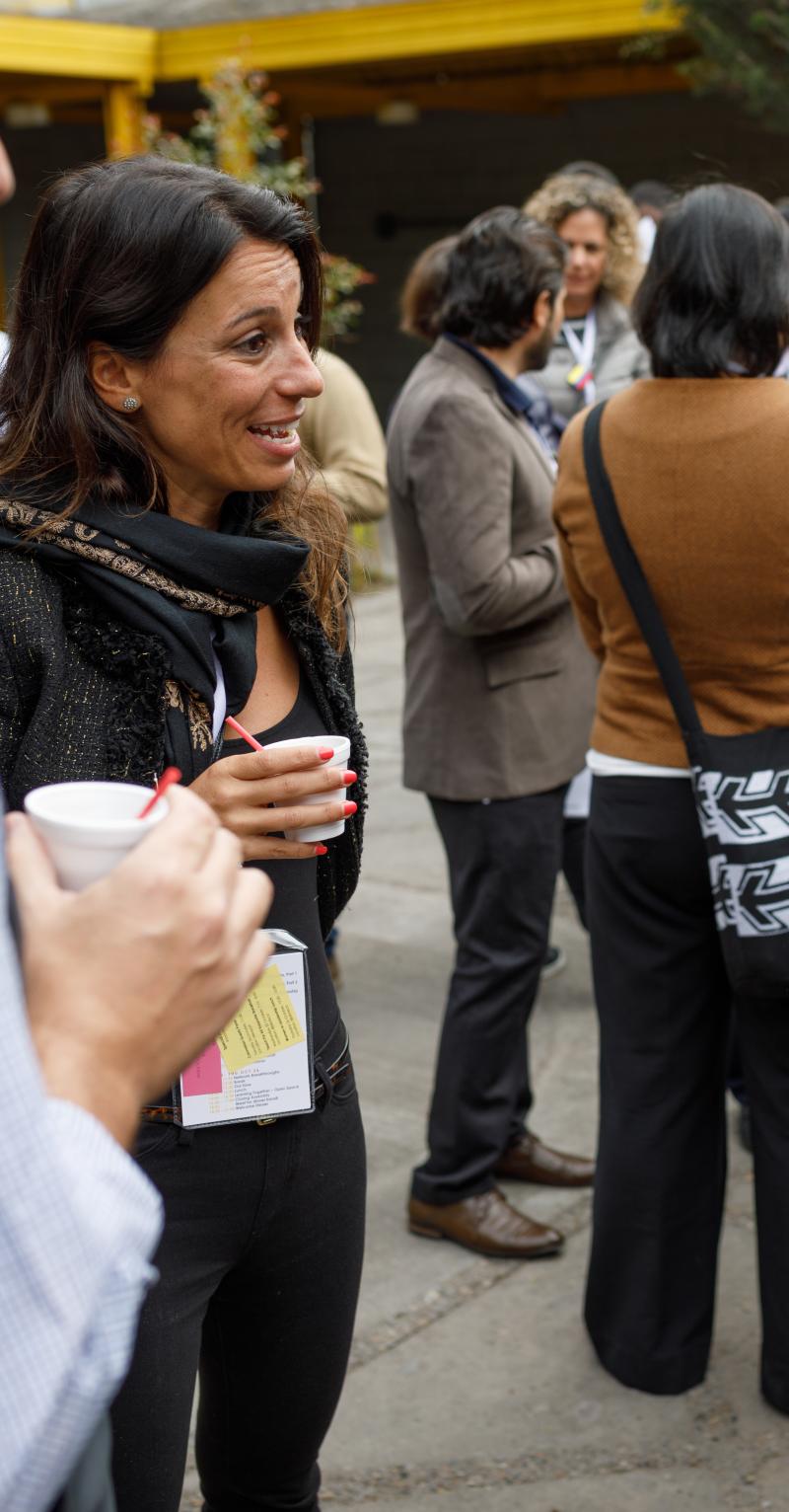 Three women and a man of diverse ethnicities smile as they speak to each other