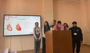 Students stand in front of a screen sharing a presentation about the heart