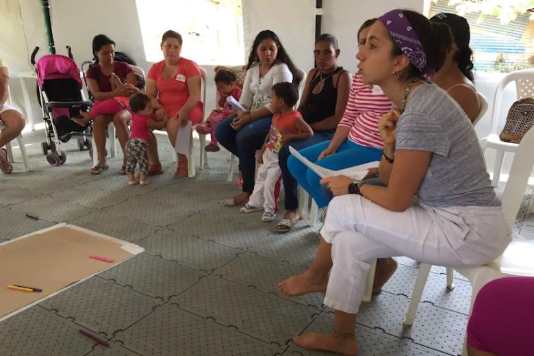 A young woman meets with a group of mothers and teenage daughters